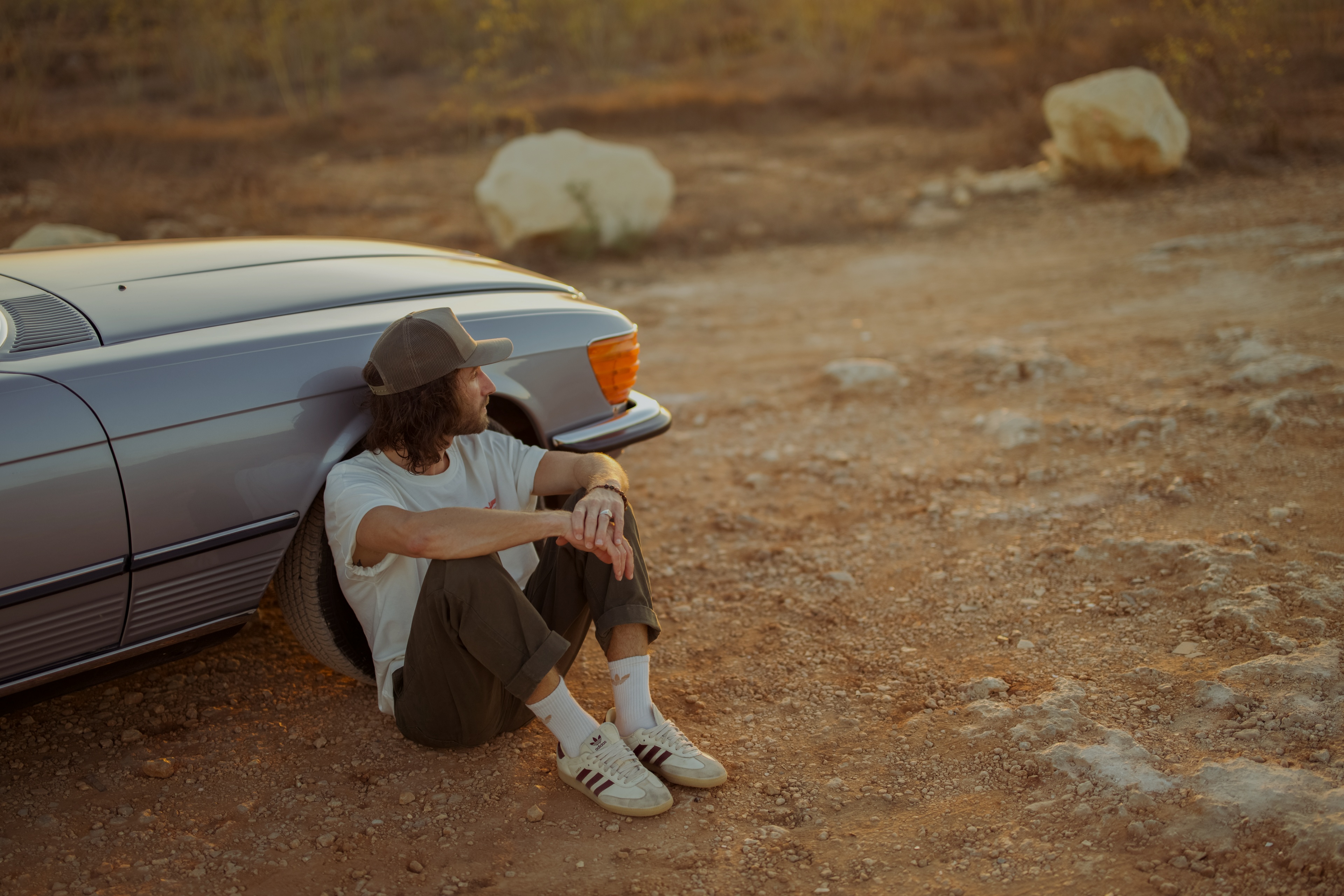 Peter Borg sitting against a vintage car, looking out