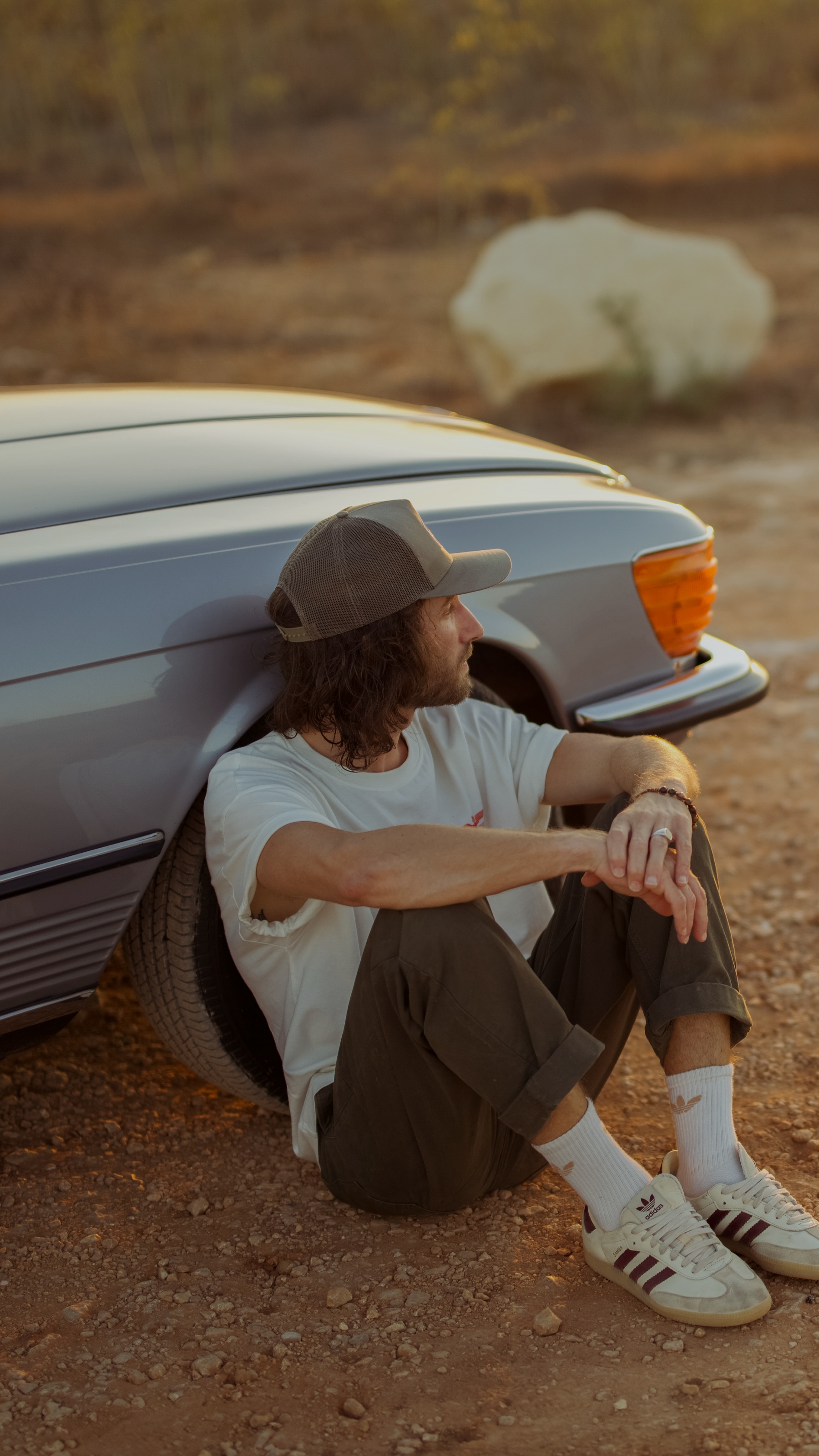 Peter Borg sitting against a vintage car, looking out